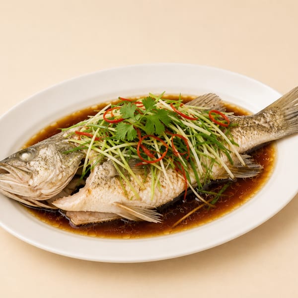 Steamed whole fish with ginger, scallions, cilantro, and red chili in a savory sauce.