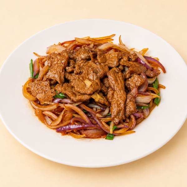 Stir-fried beef with red and white onions and green scallions on a white plate.