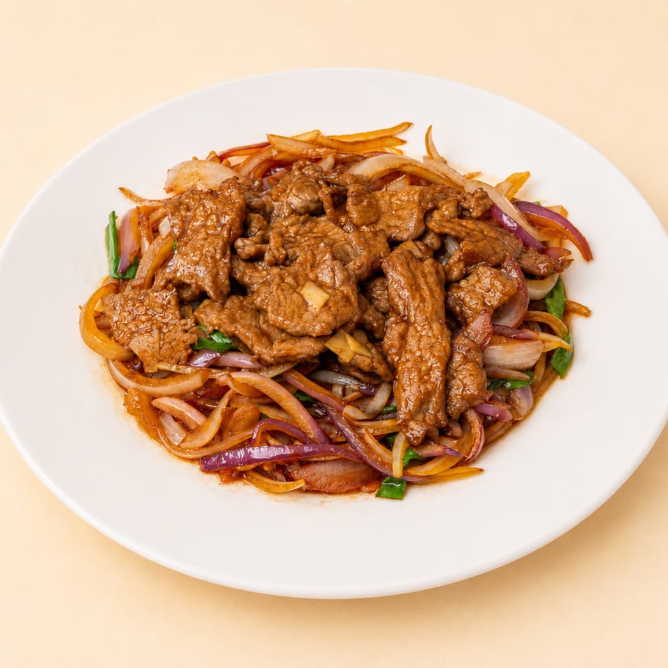 Stir-fried beef with red and white onions and green scallions on a white plate.