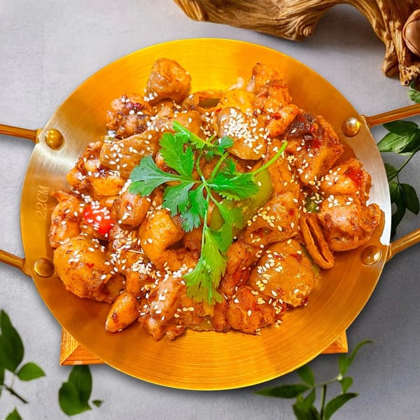 Ginkgo Chinese Restaurant's spicy chicken dish, garnished with sesame seeds and cilantro, served in a golden pan.