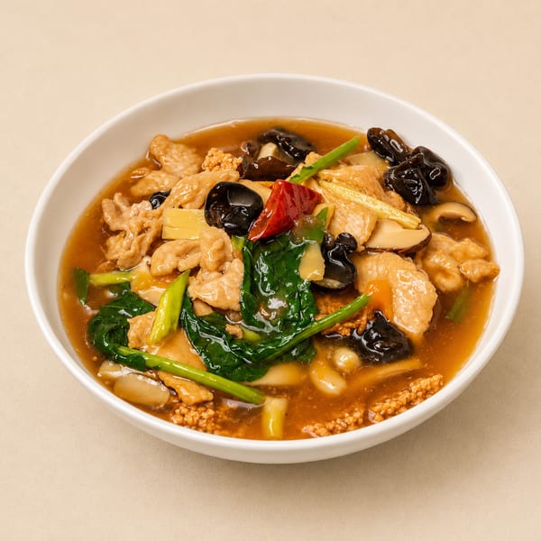 A white bowl filled with a savory dish featuring chicken, mushrooms, and green vegetables in a rich sauce.